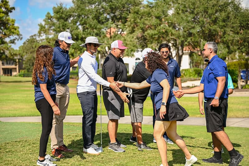 People shake hands on a golf course.