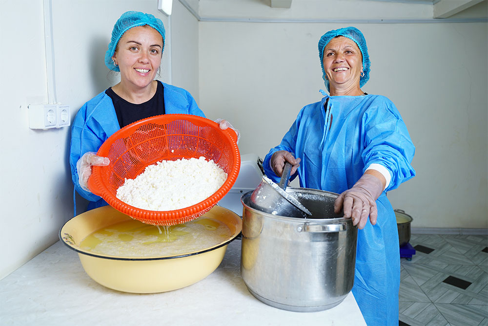 Two women in protective sterilization clothing process milk products.