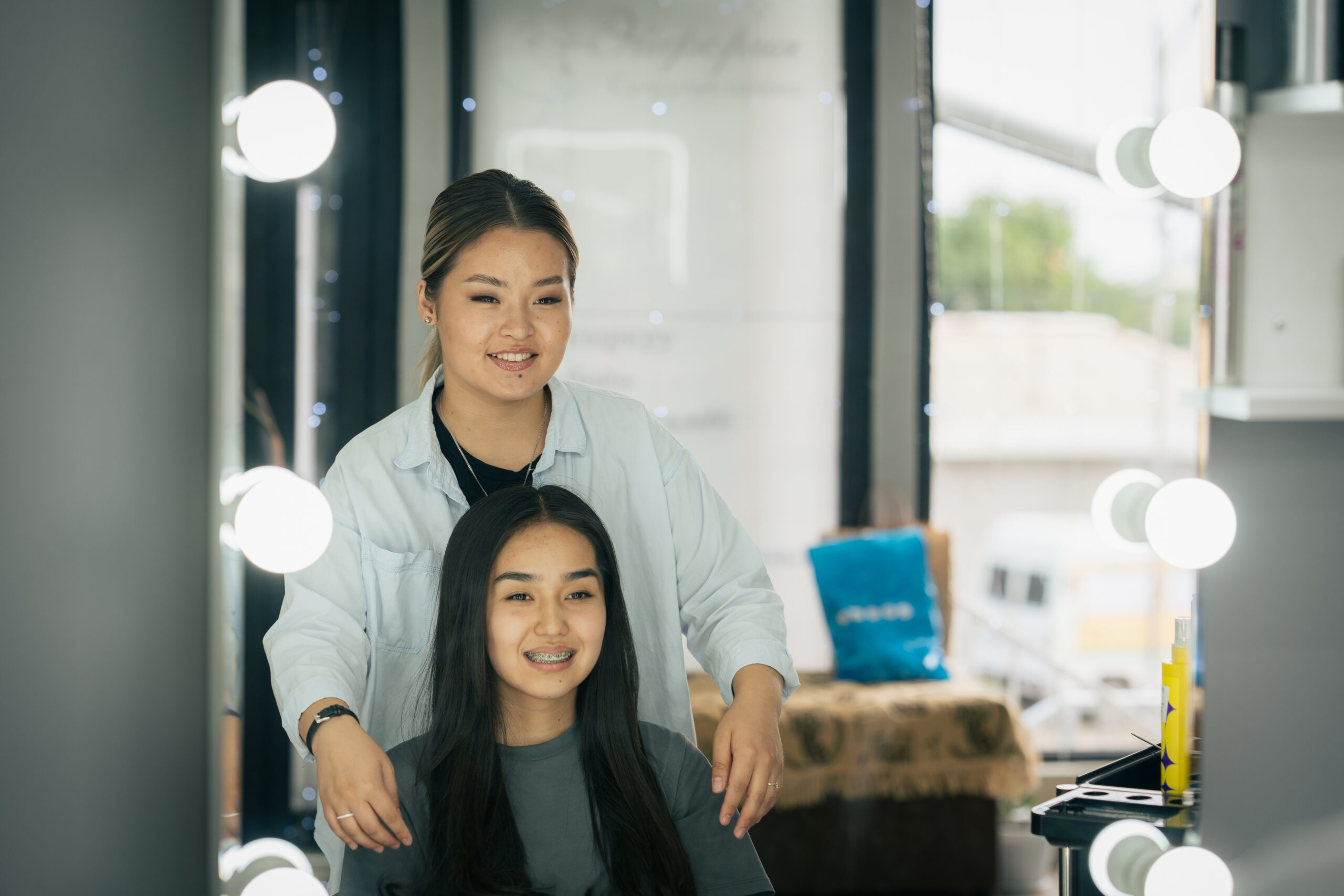 Ayana stands behind a client admiring her hairstyle.