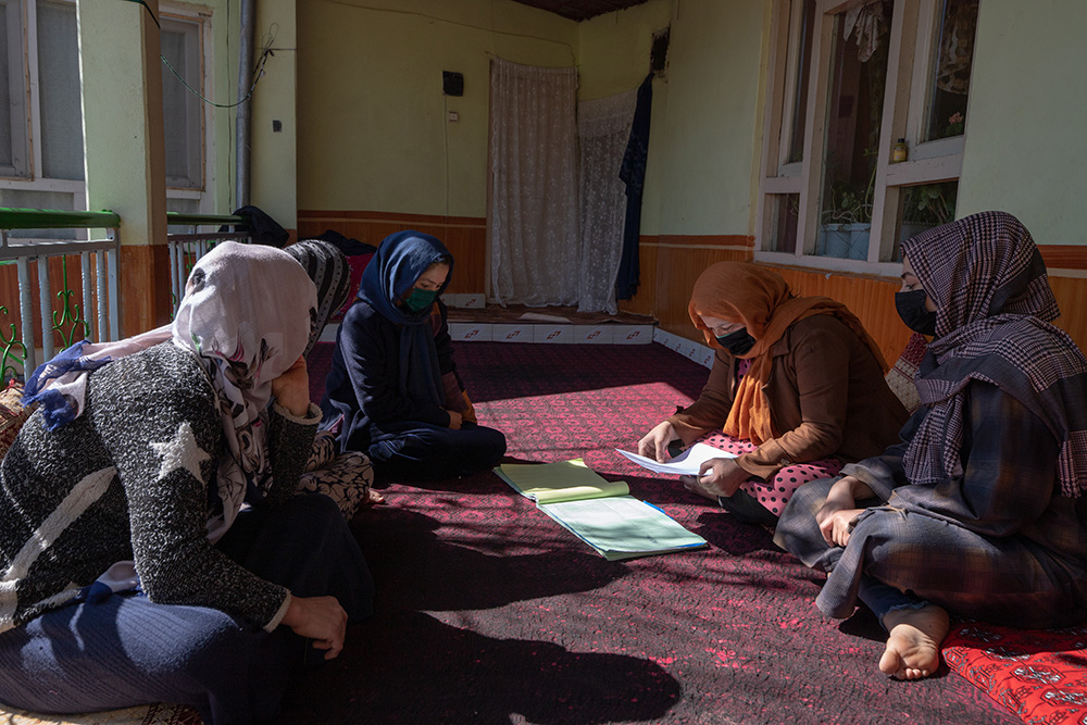 A group of women in Afghanistan review paperwork related to their CBSG.