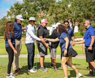 People shake hands on a golf course.