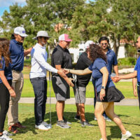 People shake hands on a golf course.